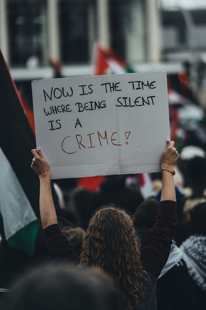A protester holds a sign reading 'Now is the time where being silent is a crime' during an urban rally.
