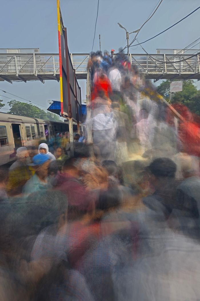 A dynamic motion blur captures crowds at a train station in Kolkata, highlighting daily life and travel.
